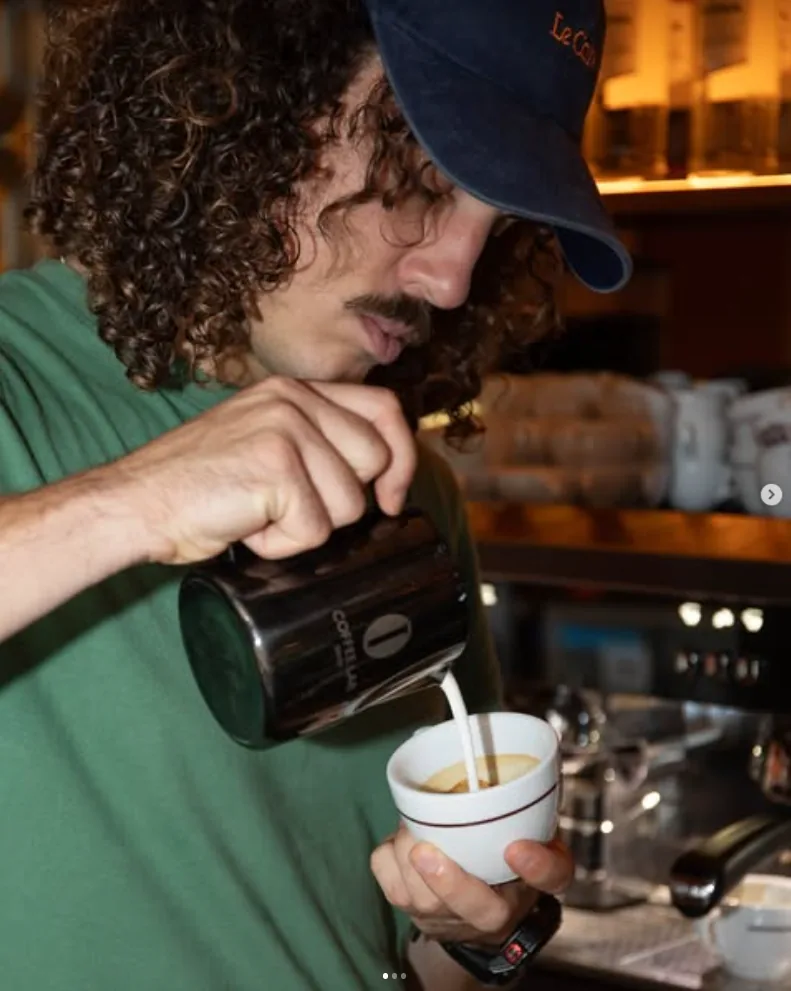 Barista pouring milk into a cappuccino
