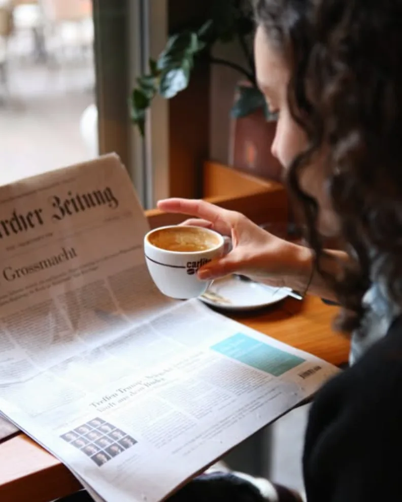 Guest reading the newspaper over an espresso